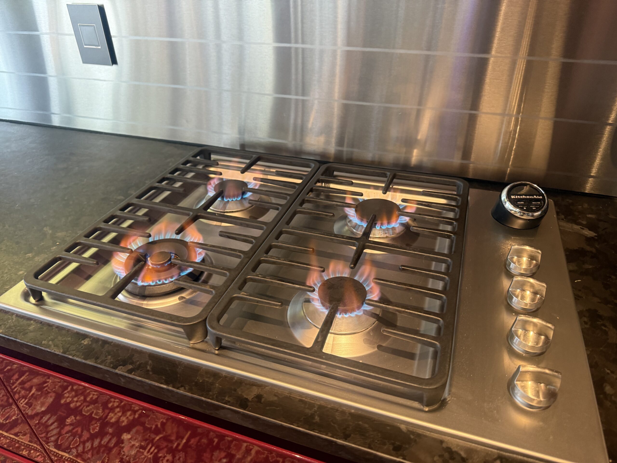 Stainless-steel gas cooktop with four burners lit