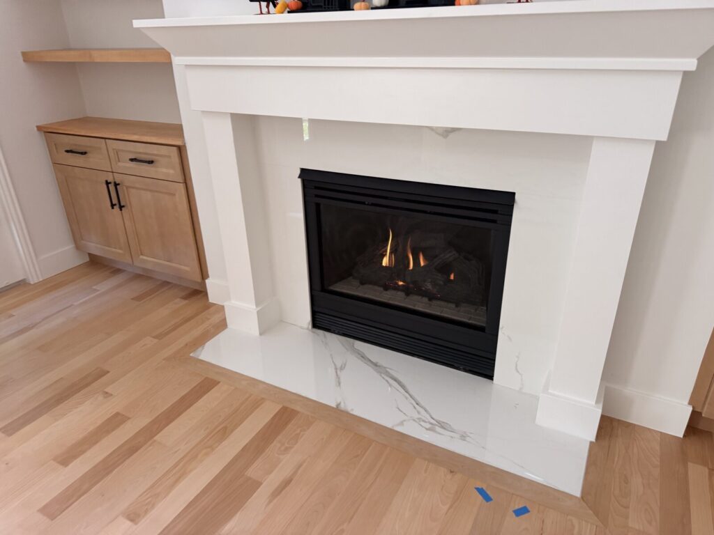 Gas fireplace with a white mantel and light stone surround.