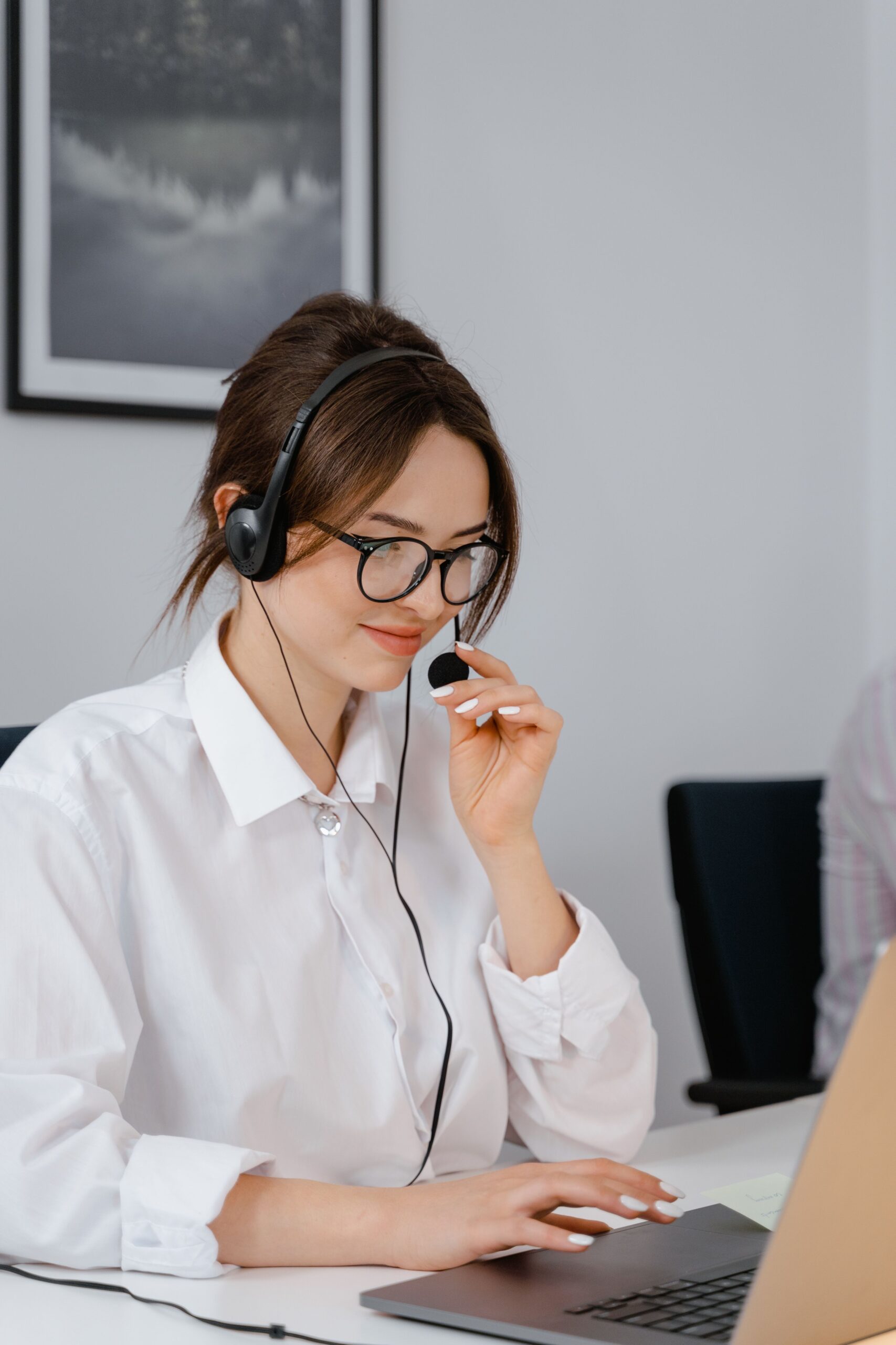 Customer-service representative wearing glasses and a headset at a laptop