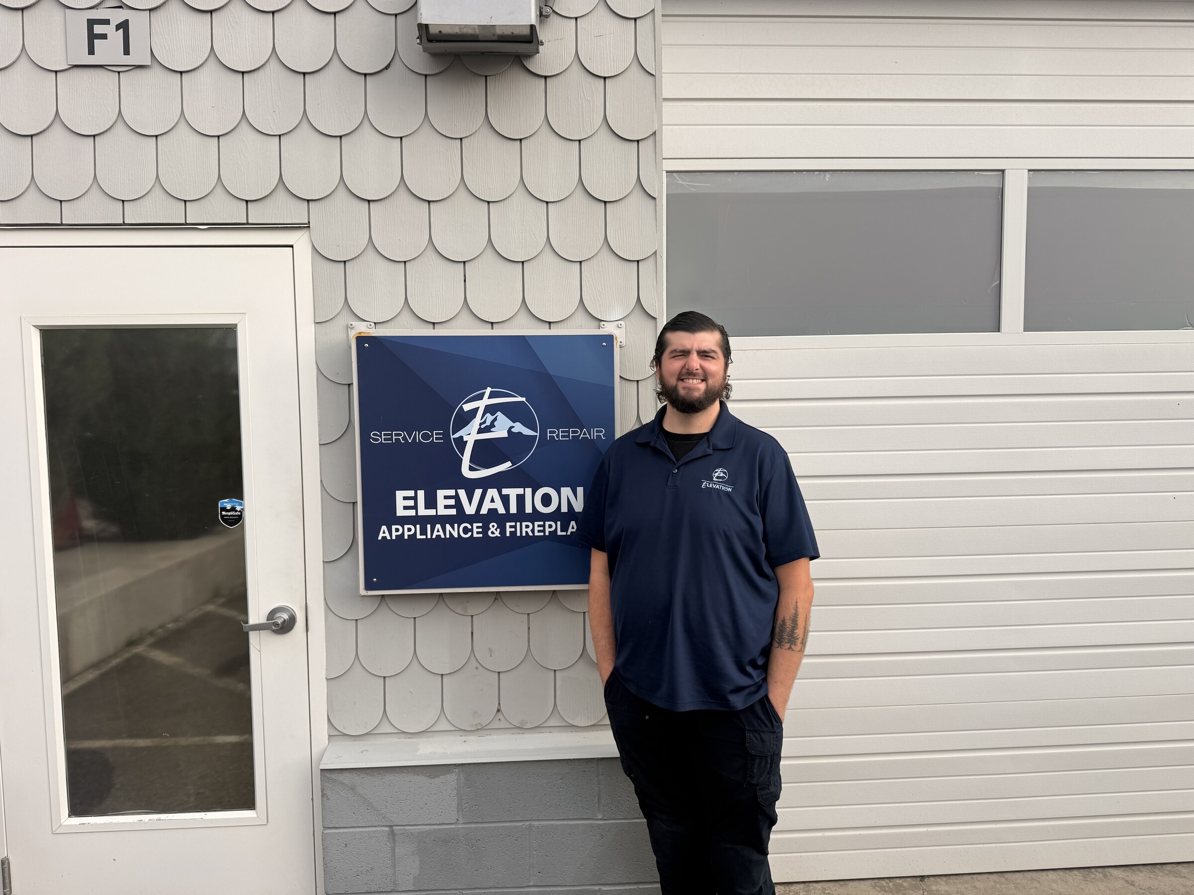 Neal standing beside the Elevation Appliance and Fireplace sign