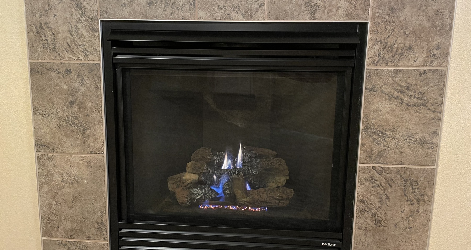 Gas fireplace burning in a stone-look tile surround